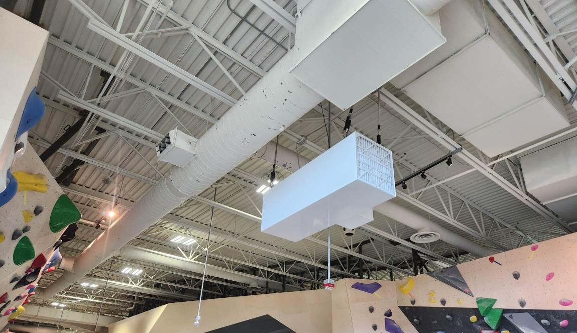 Climbers at a busy indoor climbing gym with chalk dust visible in the air